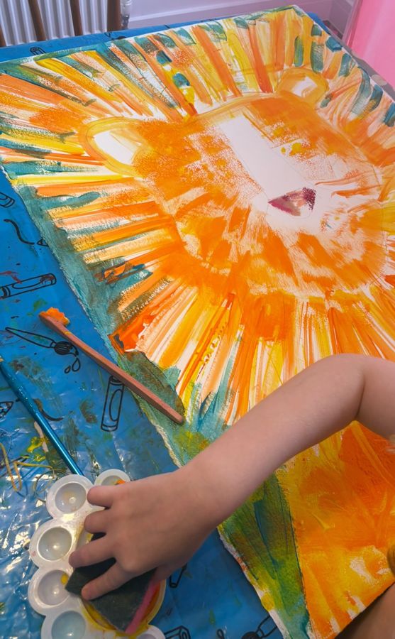 Ada painting a big orange lion with a sponge
